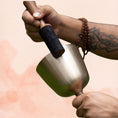Load image into Gallery viewer, Handle Singing Bowl with brass body and attached handle, being played with a wooden mallet.