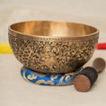 Load image into Gallery viewer, Antique style Ganesha engraved Singing Bowl with warm brass finish, blue cushion and wooden mallet.