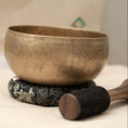 Load image into Gallery viewer, Kopre Singing Bowl for heart and crown chakra with aged brass finish, black cushion and wooden mallet