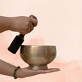 Load image into Gallery viewer, Naga Singing Bowl tuned to D5 and A3 with aged brass finish, held in hand with wooden mallet