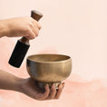 Load image into Gallery viewer, Naga Singing Bowl for Solar Plexus Chakra with aged brass finish, held in hand with wooden mallet.