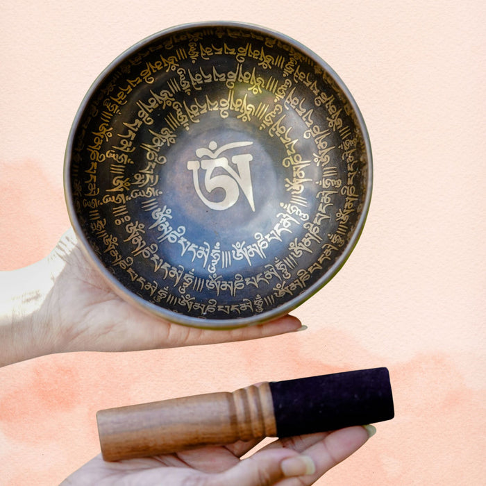 Universal Sound AUM Singing Bowl with Om symbol, mantra-style border, dark aged brass interior and wooden mallet.