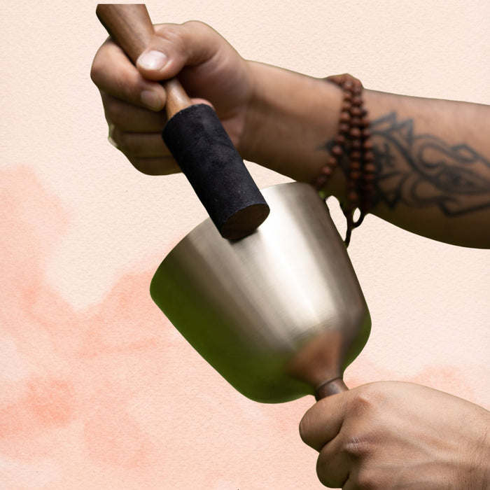 Handle Singing Bowl with brass body and attached handle, being played with a wooden mallet.