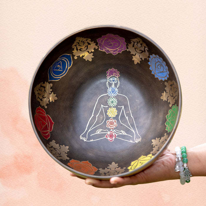Top view of a 7 Chakra Singing Bowl featuring a meditating figure inside with seven chakra symbols around the inner wall.