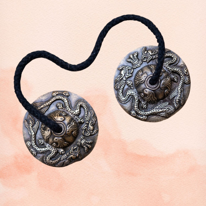 Dragon-carved tingsha cymbals with aged metal finish and connecting cord.