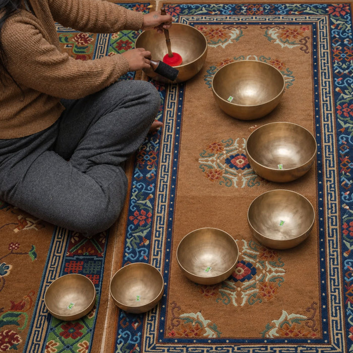 Himalayas Singing Bowl Chakra Set with seven brass bowls arranged by size on a quiet listening rug.