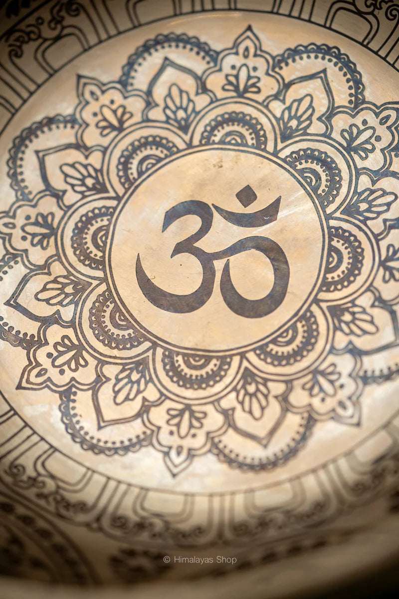 Om Mandala carved singing bowl with central Om symbol, detailed floral mandala engraving, repeated Om motifs.