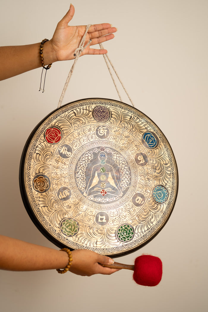 Chakra Gong with meditating human artwork, colourful chakra symbols and red mallet for sound practice.